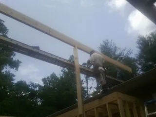 Carpenter setting a ridge beam over a new addition frame — Ice Dam Removal by Roofing Brothers in Cochrane