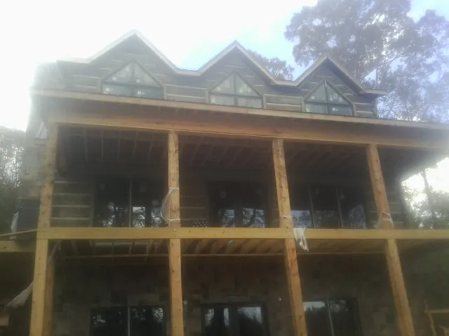 Dormers and porch framing on a large log home under construction — Roof Coating work by our crew in Cochrane