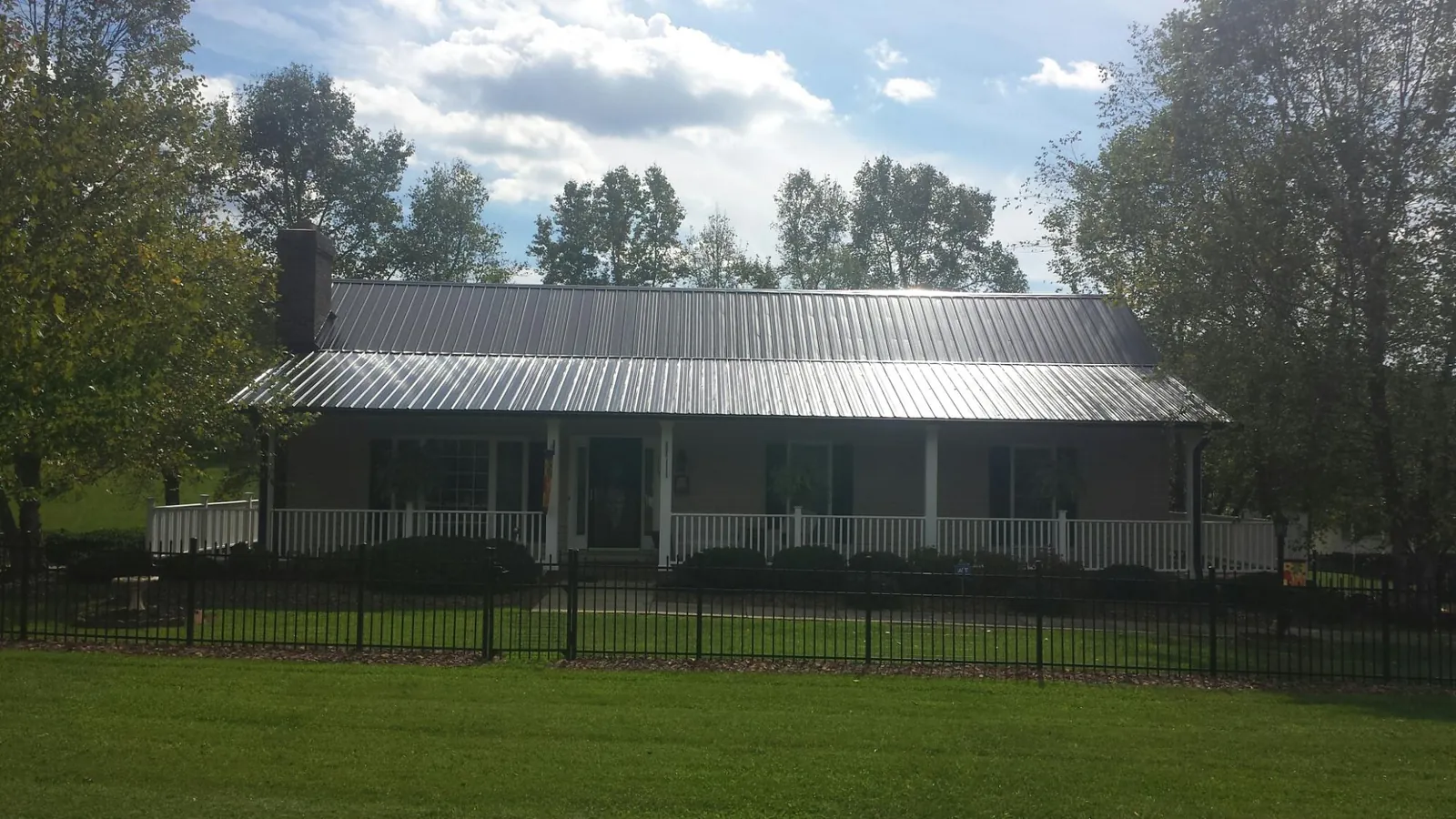 Gray metal roof on a brick ranch with a full width front porch — Gutter Guard Installation work by our crew in Cochrane